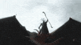 a man is riding on the back of a dragon while holding a cane .