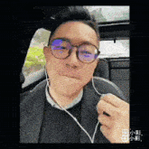 a man wearing glasses and ear buds looks at the camera