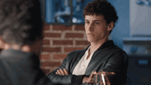 a man with his arms crossed looks to the side
