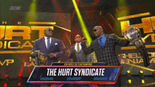 a man in a suit is holding a trophy with the words the hurt syndicate on the bottom