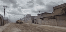 a military vehicle is driving down a dirt road in a residential area