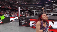 a woman in a wrestling ring with a sign that says " raw "