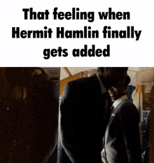 a man in a suit and tie is standing in a dark room with the caption that feeling when hermit hamlin finally gets added
