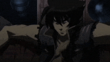 a man with long black hair is sitting in a chair with his arms crossed