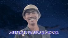 a man wearing a helmet and smiling with the words meledak pasukan mokel written in purple