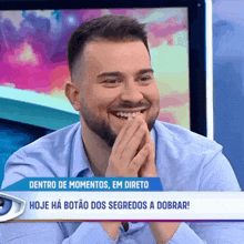 a man with a beard is smiling in front of a tv screen that says dentro de momentos