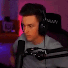 a man wearing headphones is sitting in front of a microphone in a room .