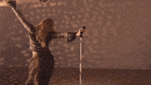 a woman singing into a microphone in front of a polka dot wall
