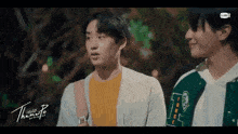 two young men are standing next to each other and talking . one of the men is wearing a green jacket .