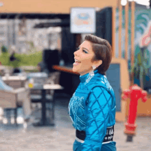 a woman in a blue jacket is laughing in front of a building