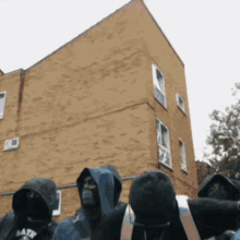 a group of people standing in front of a brick building with a hoodie that says death