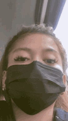 a close up of a woman wearing a black face mask .
