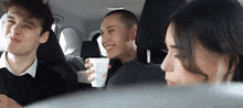 a group of people in a car one of whom is holding a cup that says so on it
