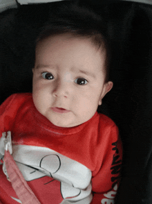 a baby wearing a red minnie mouse sweater looks at the camera