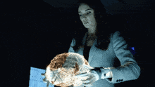 a woman in a suit is holding a glowing brain in her hands