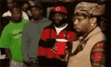 a group of men are standing next to each other and one of them is holding a red cup .