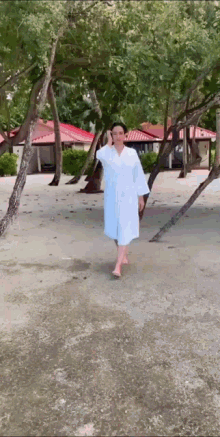 a woman in a white robe is walking on a beach