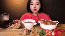 a woman in a red shirt is eating a variety of food