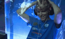 a man wearing headphones and a blue teamliquid shirt