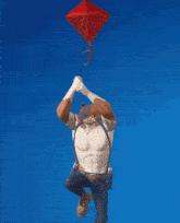 a man with a cat head is holding a red kite over his head