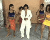 a woman in a white suit is surrounded by other women in colorful outfits