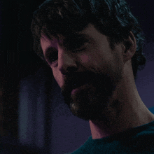 a close up of a man 's face with a beard in a dark room