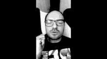 a man wearing glasses and a ring on his finger is talking on a cell phone .