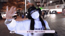 a woman wearing a mask and a hat is waving at the camera
