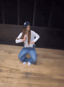 a woman in a white shirt and blue hat is kneeling on a wooden floor