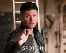 a man in a jacket is pointing at the camera with his finger .