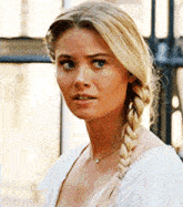 a woman with a braid in her hair is wearing a white shirt and a necklace