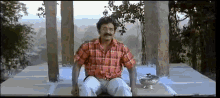 a man in a plaid shirt is sitting on a table in front of a bowl .