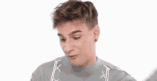 a young man wearing a gray sweater is making a funny face and saying `` you know '' .