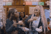 two women with pink hair are eating food in a restaurant ..