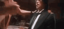 a man in a tuxedo is being punched by another man in a boxing ring .