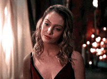 a woman in a red dress is smiling and looking at the camera with candles in the background