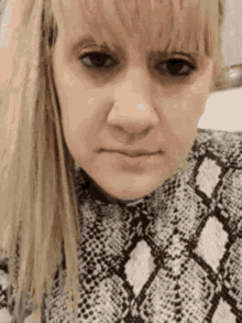 a close up of a woman 's face with a snake print sweater on .
