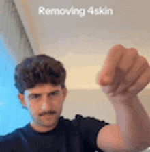 a man with a mustache is holding his fist up in the air while wearing a black shirt .