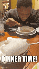 a young boy is sitting at a table with a bowl of soup and the words dinner time