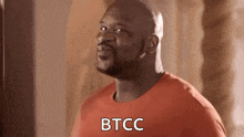 a bald man with a beard is wearing a red shirt and making a face .