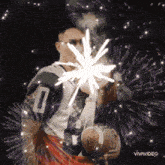a football player with the number 0 on his jersey is holding a firework display