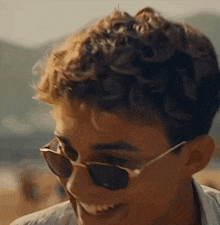 a young man wearing sunglasses is smiling and looking at the camera