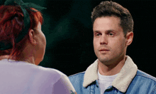 a man in a denim jacket is talking to a woman
