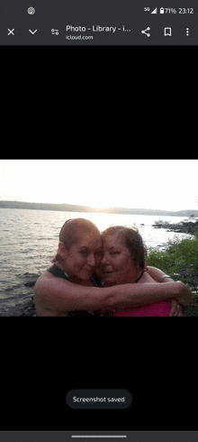a screenshot of two women hugging each other in front of a lake ..