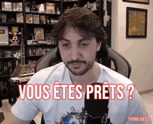 a man sitting in front of a microphone with the words " vous etes prets " on his shirt