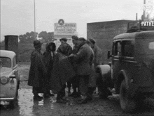 a black and white photo of a group of men standing in front of a sign that says pathe