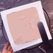 a person is holding a white plate with a piece of chocolate frosting on it