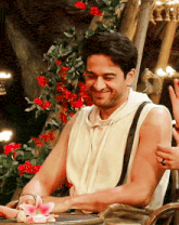 a man in a white shirt is smiling in front of a flower