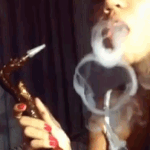 a woman is blowing smoke out of a hookah .