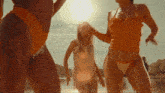 three women in bikinis are dancing in the sun